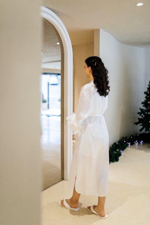 A woman in a white robe looking at a mirror