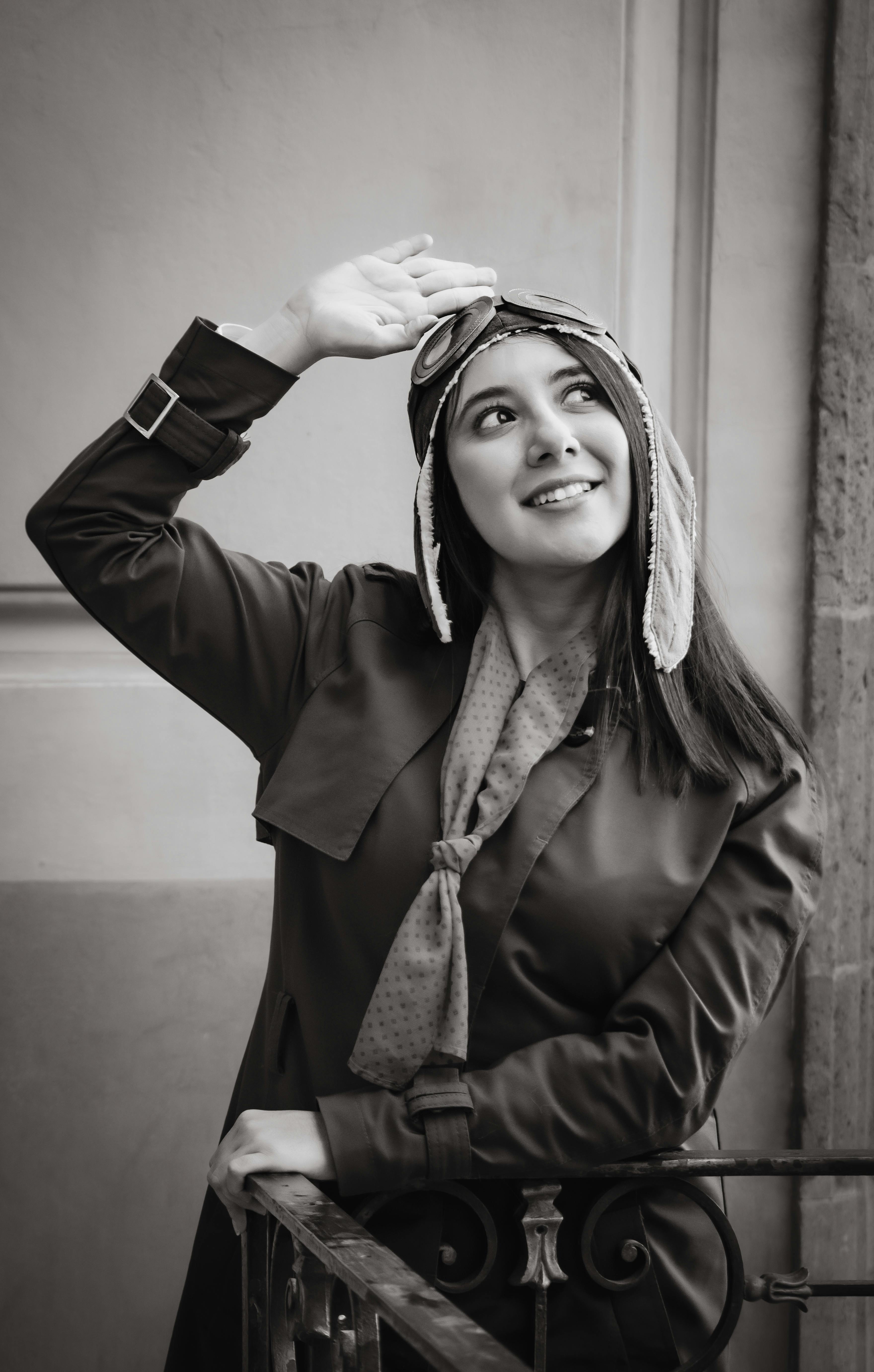 Free Charming black and white portrait of a smiling woman in an aviator hat, looking up. Stock Photo