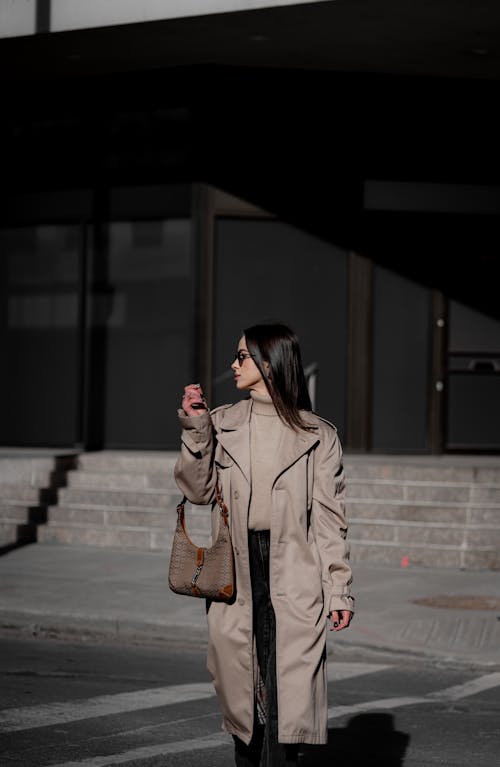 A woman in a trench coat and black pants walking down the street