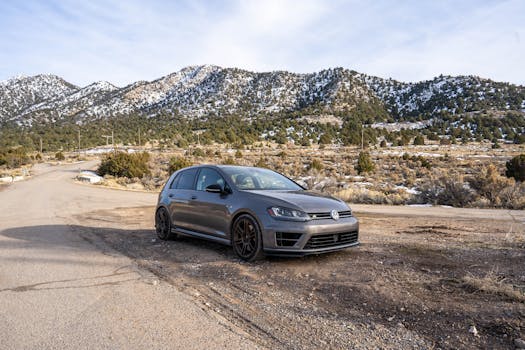 A grey Volkswagen Golf parked by a roadside with a scenic mountain backdrop, ideal for travel themes.