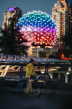 Woman and dog enjoy a serene moment near Vancouver's Science World at dusk.