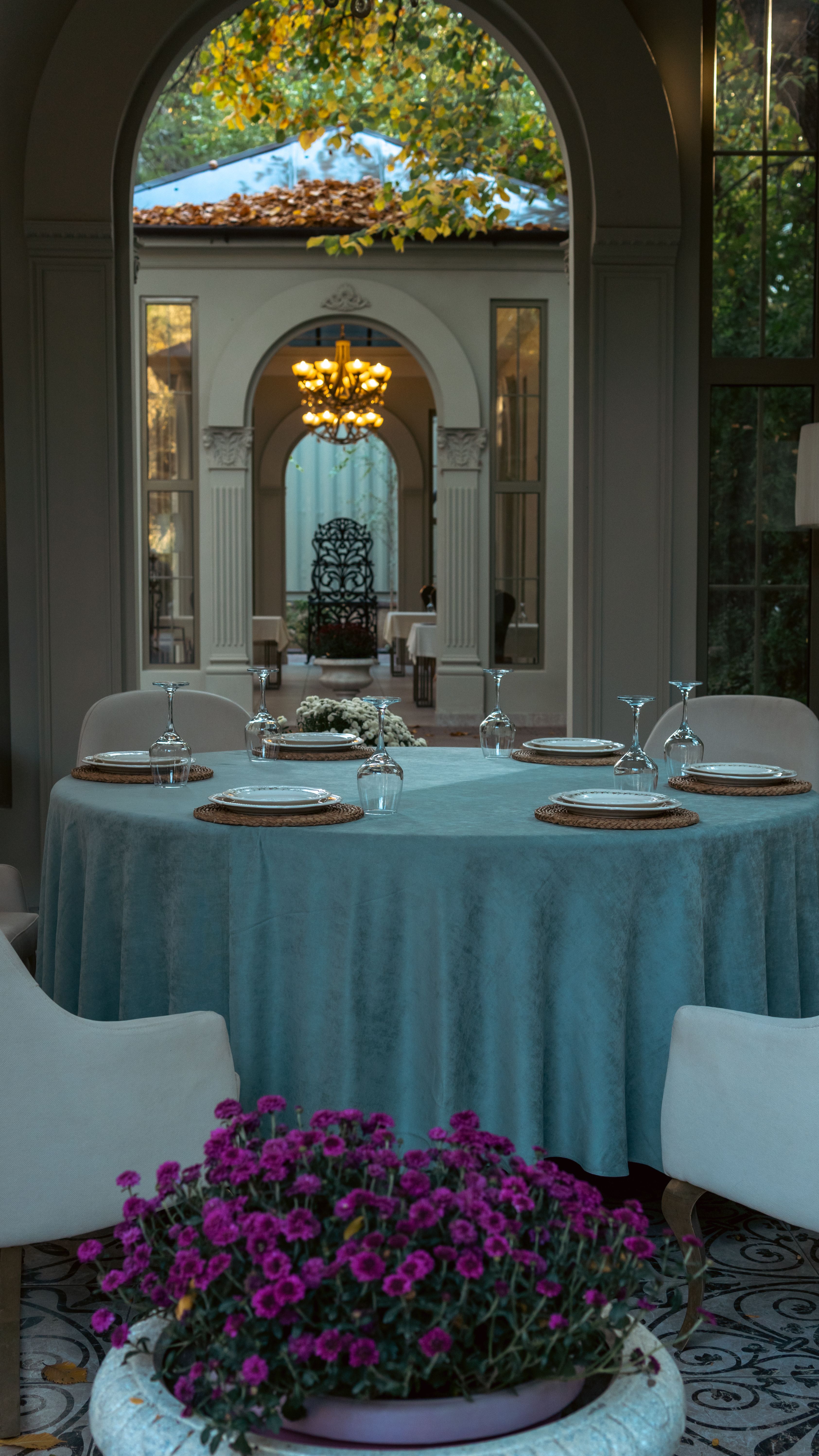 Beautifully set table in an elegant venue with an arched entry, showcasing classic decor and greenery.