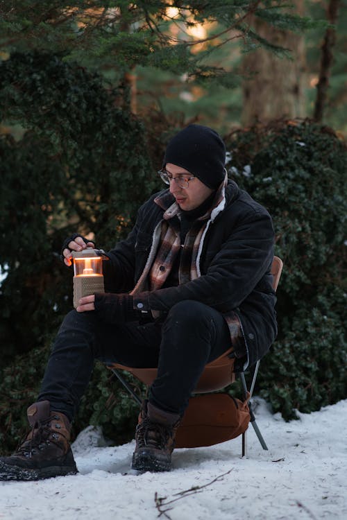 Man in Jacket Sitting with Lantern in Winter