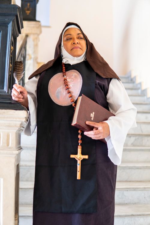 Free A contemplative nun standing on a staircase, holding a Bible in Mexico City. Stock Photo