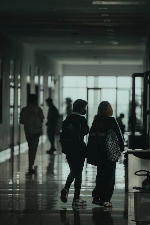 Two people walking down a hallway in a school