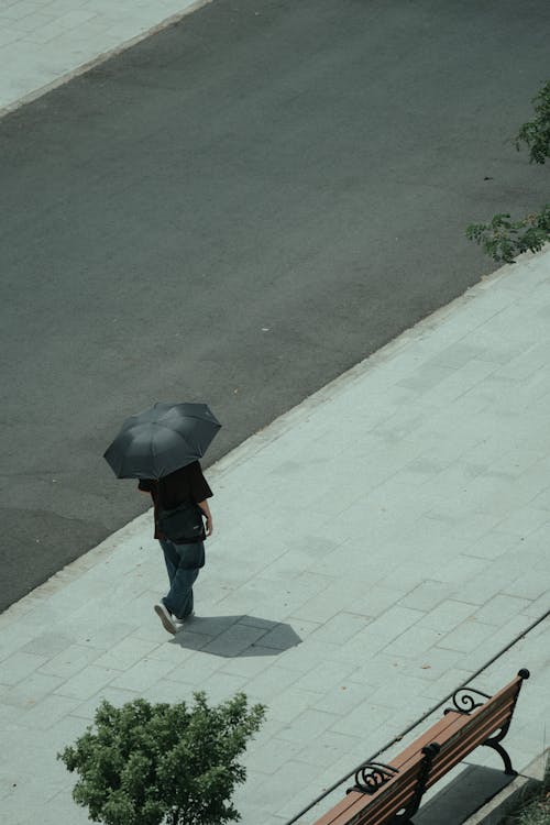 A person walking down a sidewalk with an umbrella
