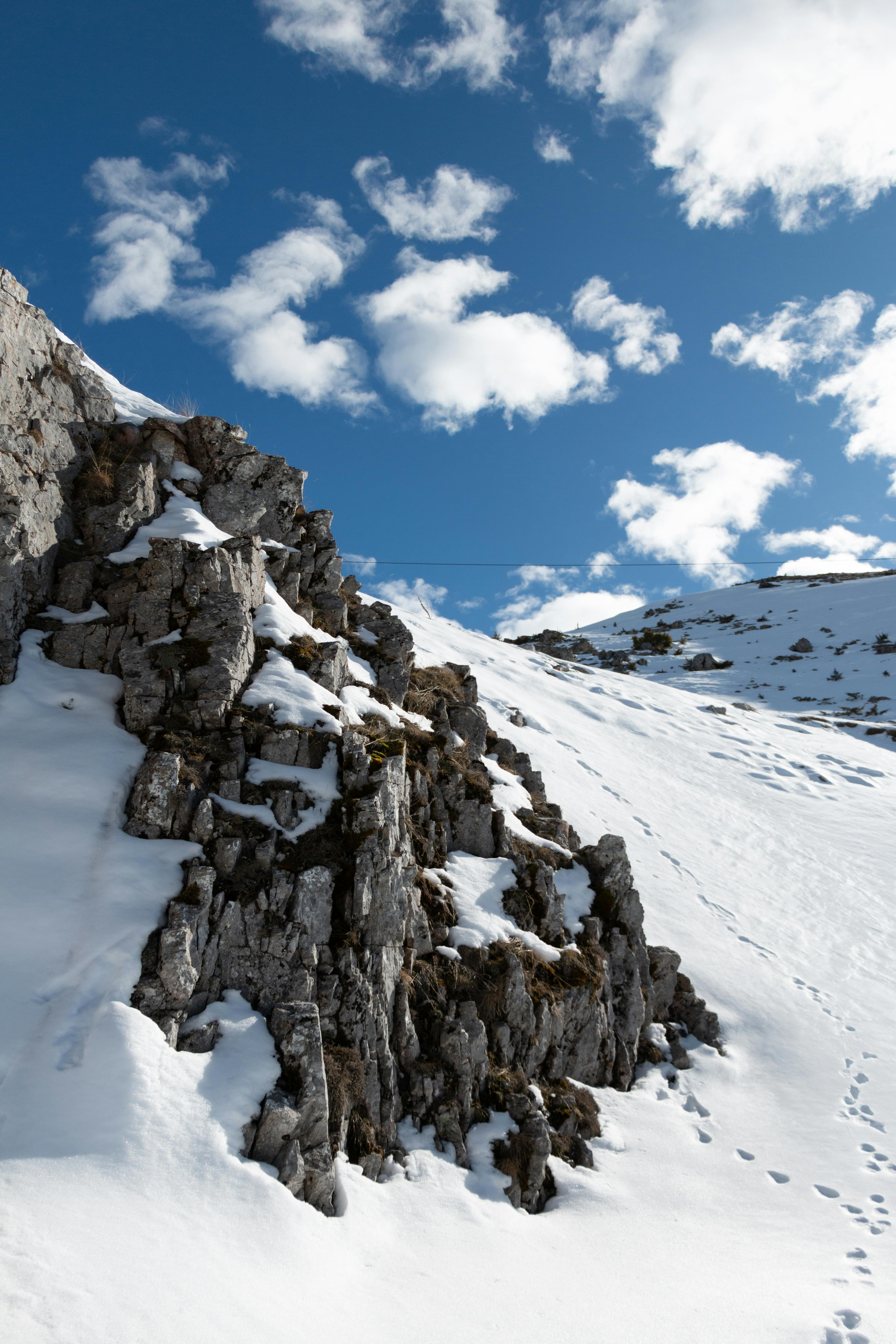 Stunning snow-covered rocky terrain under a bright blue sky in Mavrovo, North Macedonia.