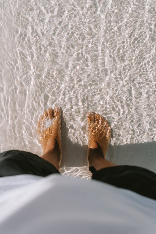 A person's feet are standing in the sand