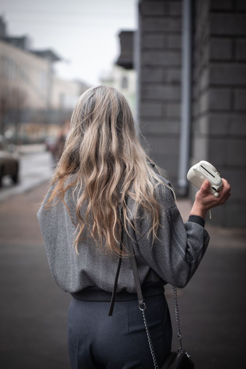 Back view of a woman with long wavy blonde hair in a grey jacket