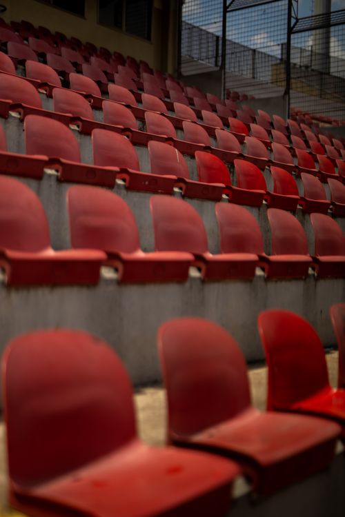 Free Rows of empty red stadium seats on a sunny day, ready for an event. Stock Photo