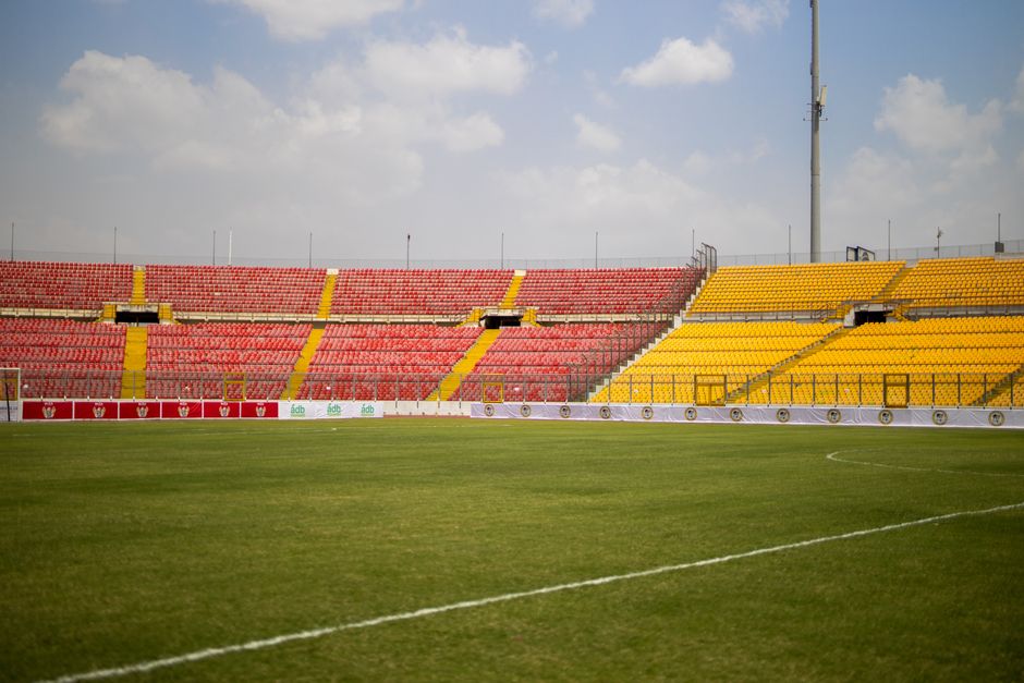 A sunny view of the empty seats and lush grass at Baba Yara Sports Stadium in Kumasi, Ghana.