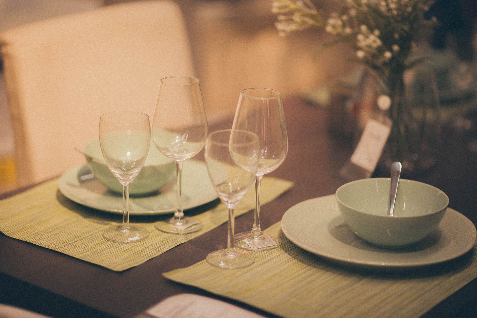 Stylish indoor table setup with pastel green tableware and glasses on a dining table.