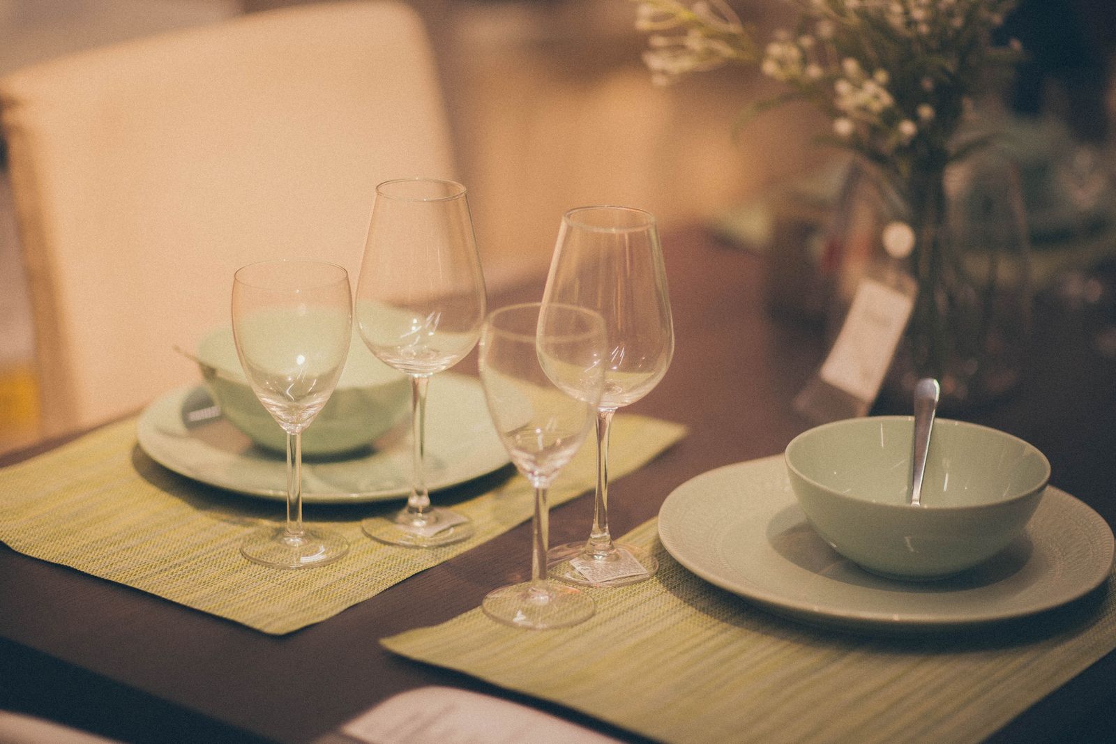 Stylish indoor table setup with pastel green tableware and glasses on a dining table.