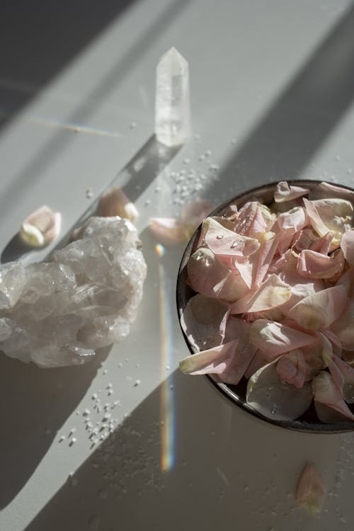 Close-up of a Bowl with Light Pink Flower Petals and Crystals on a White Table 