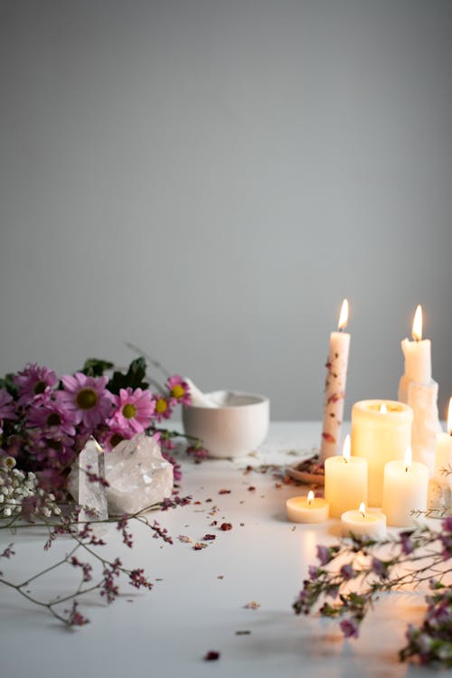 Burning Candles, Flowers and Crystals Lying on a White Table 