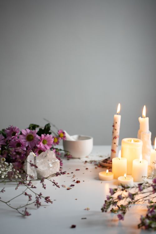Free A calming arrangement of candles, flowers, and crystals on a white table. Stock Photo
