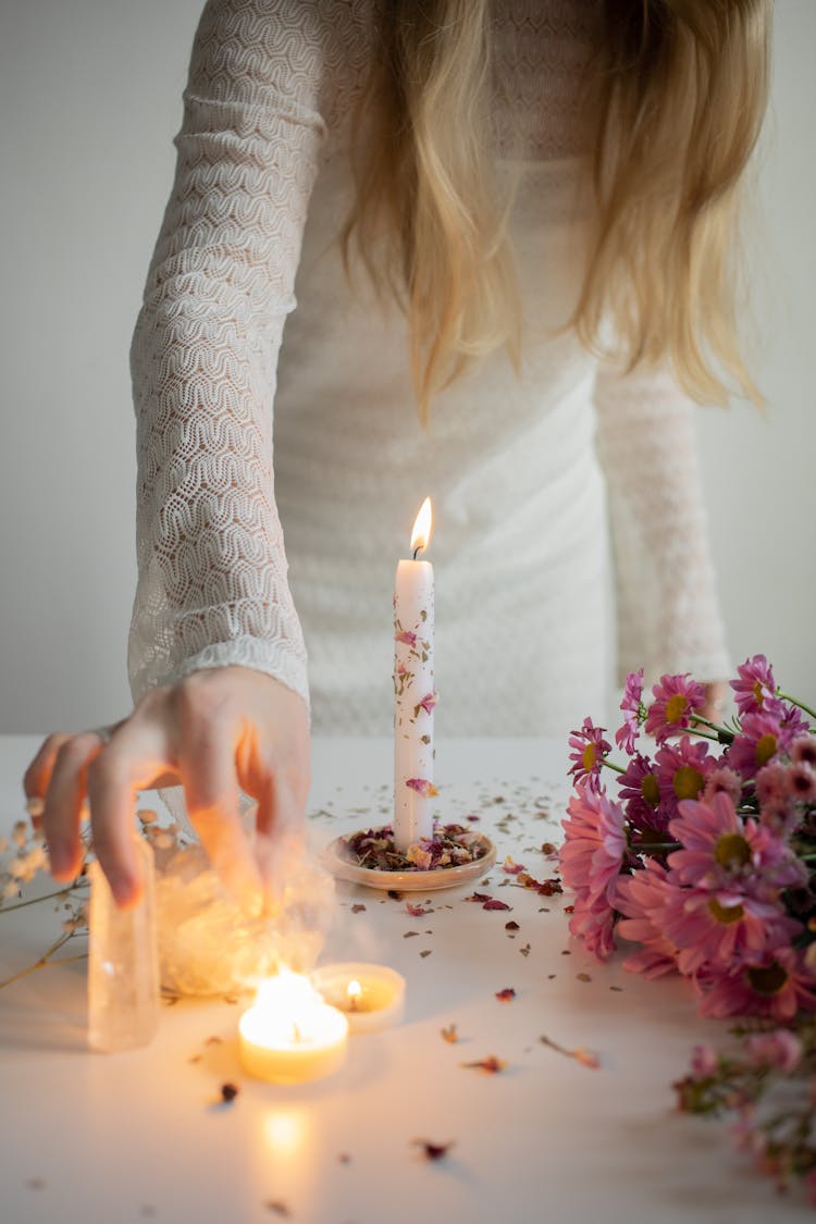 Woman Standing Next To A Table With Burning Candles, Flowers And Crystals 