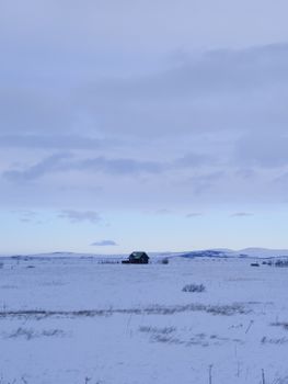 Lonely wooden barn on snowy plains in Rangárþing eystra, Iceland.