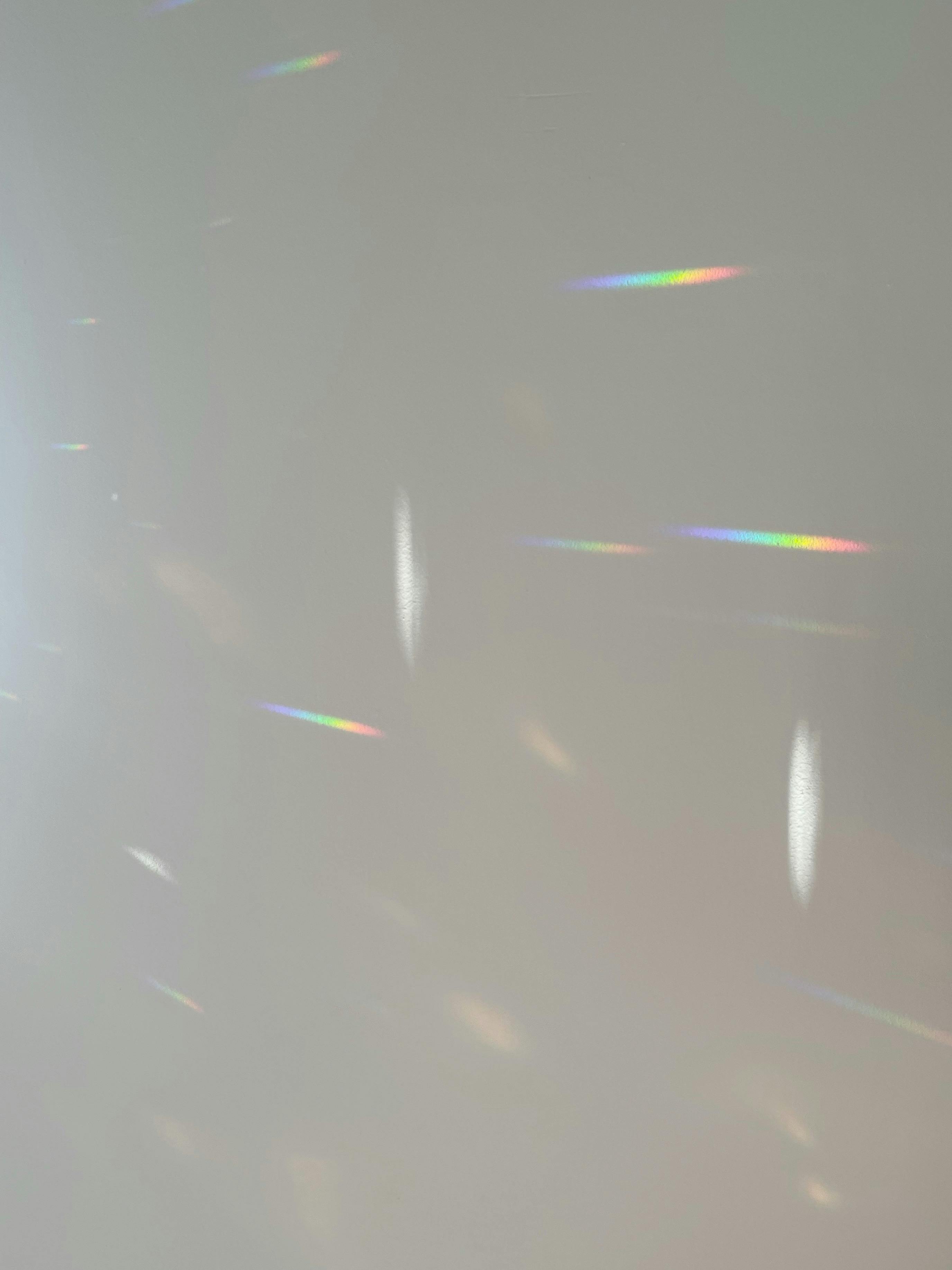 Soft rainbow reflections on a plain wall creating an abstract and serene effect.