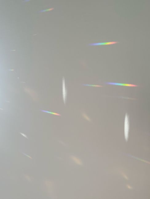 Soft rainbow reflections on a plain wall creating an abstract and serene effect.