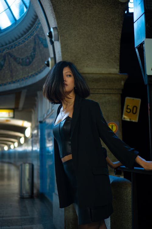 A woman in a black jacket and skirt standing in an underground station