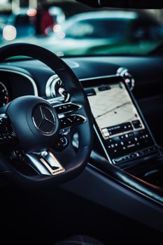 Close-up of a luxury car interior focusing on the dashboard and steering wheel, featuring modern design elements.