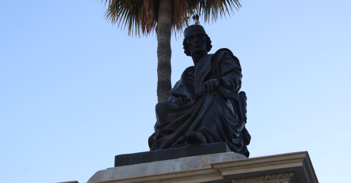 Bronze statue of Elio Antonio de Nebrija at a prominent Lebrija landmark under a clear sky.