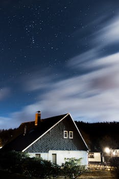 A charming house in Jonsdorf, Germany, under a starry night sky with moving clouds.