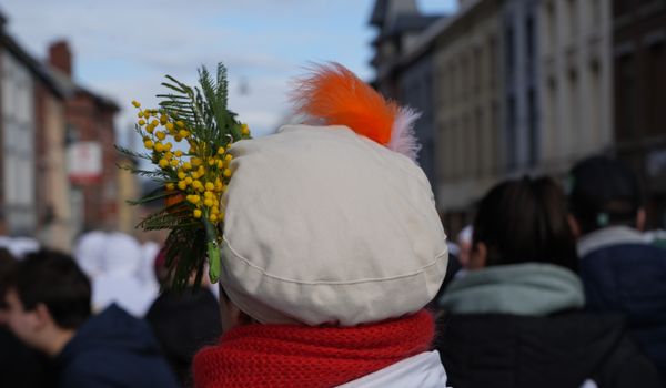 A vibrant street scene during a festival in Binche, Belgium, showcasing colorful attire and joyful crowds.