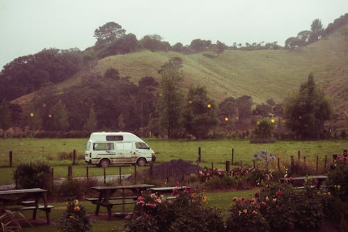 A van parked in a field next to a picnic table