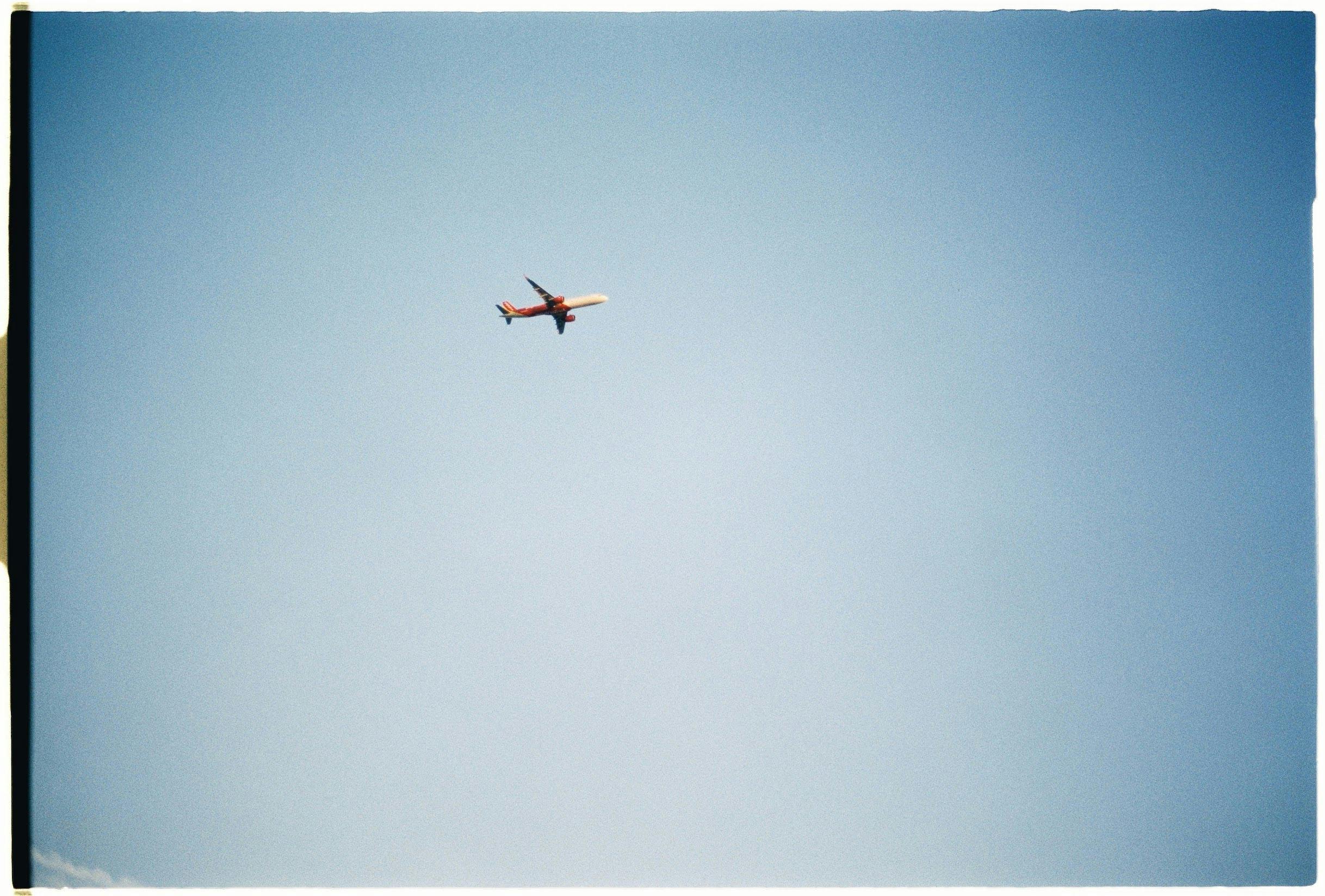A solitary airplane soars through a clear blue sky with ample copy space.