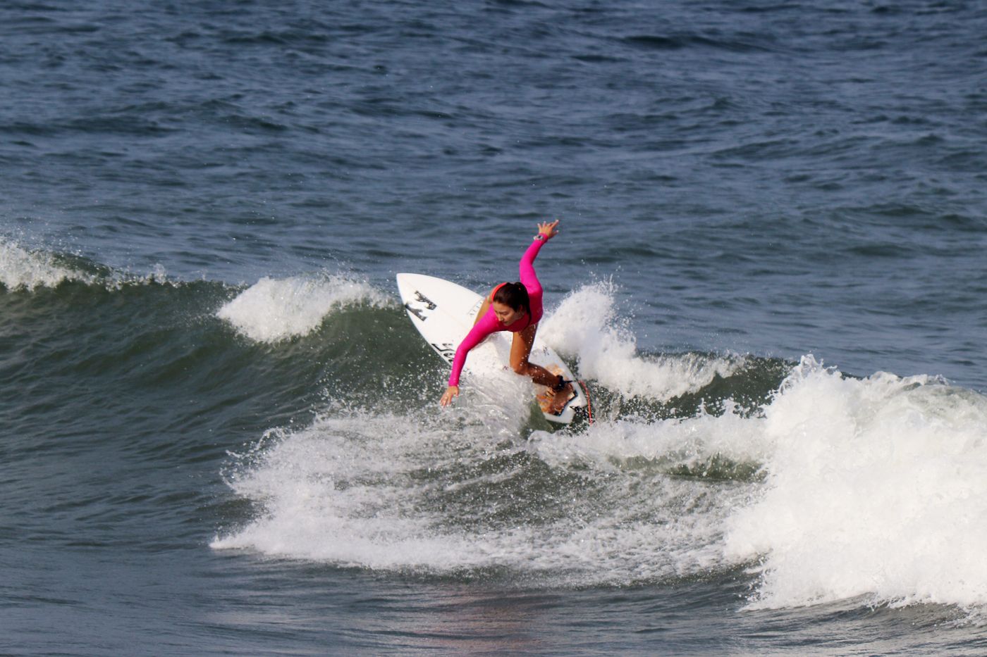 A woman skillfully rides a wave on her surfboard, showcasing surfing skills and ocean adventure.