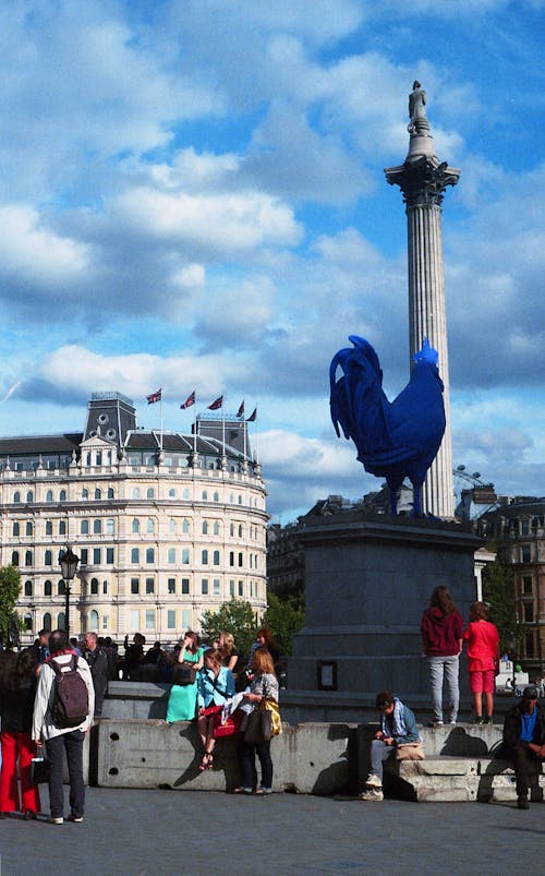 Free People Standing Below Rooster Statue by the Building Stock Photo