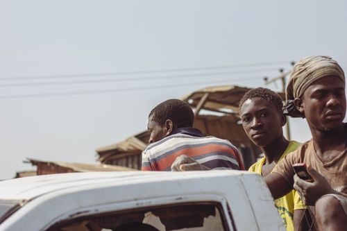 Free Group of young men riding in the back of an open truck in a rural area of Abuja, Nigeria. Stock Photo