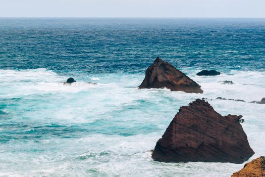 Waves crashing against rugged cliffs in Madeira, Portugal, showcasing breathtaking ocean views.
