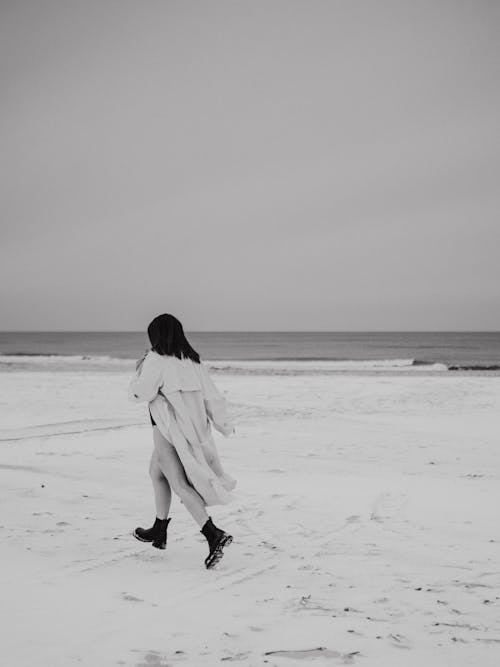 A woman running on the beach in black and white