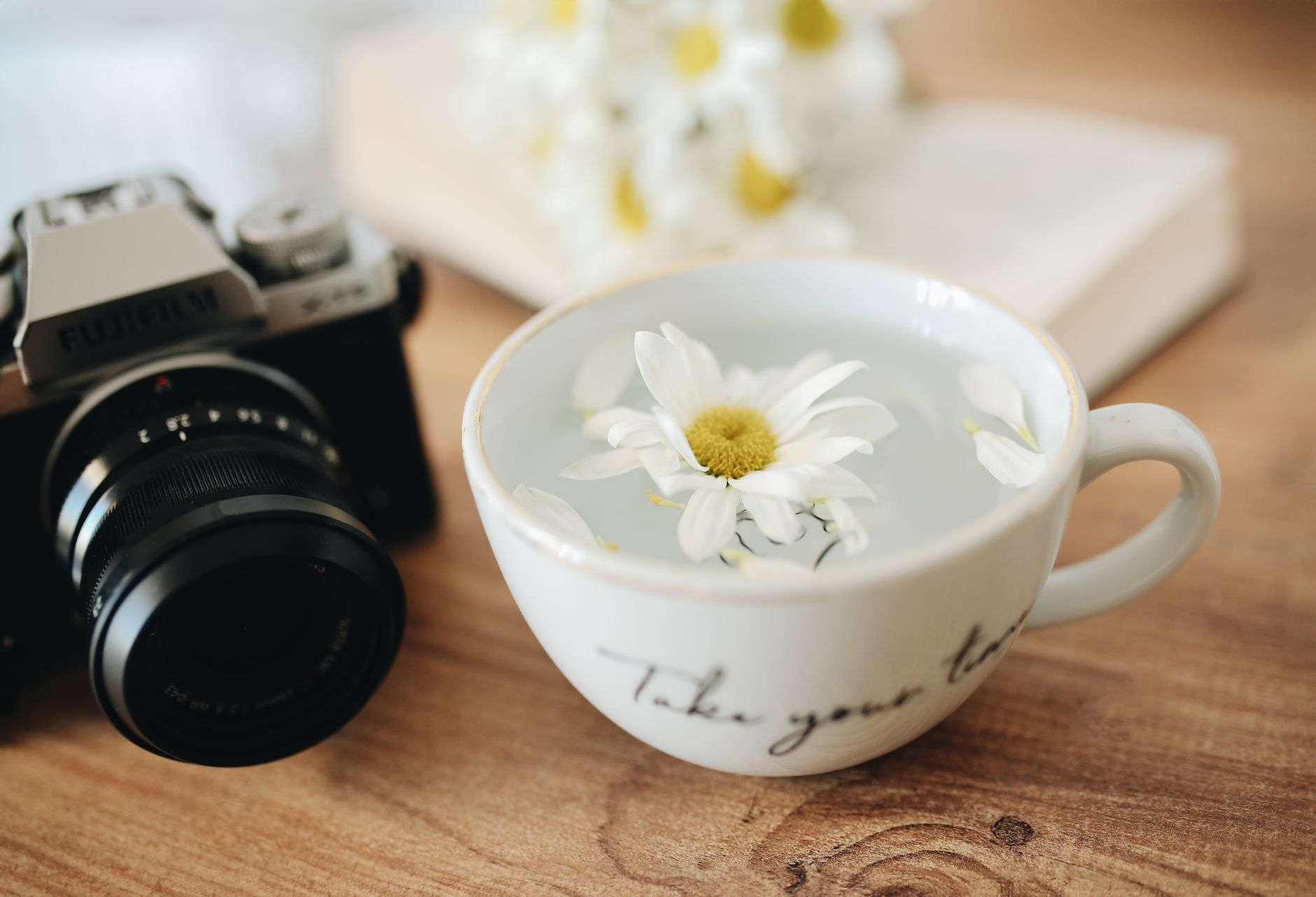 Apigenin sleep supplement — A serene still life composition featuring chamomile tea, flowers, and a vintage camera on a wooden table.