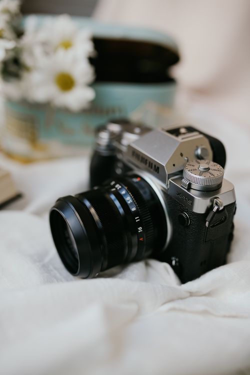 Free Close-up of a vintage camera and flowers on a soft white fabric background. Stock Photo