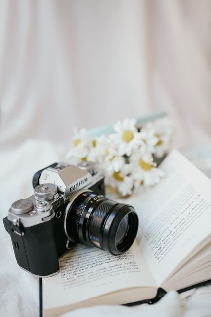 A classic film camera on an open book with daisies in the background, providing nostalgic vibes.