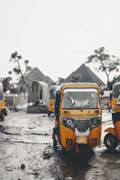 Free Vibrant auto rickshaws parked on a rainy street in Abuja, showcasing Nigerian urban life. Stock Photo