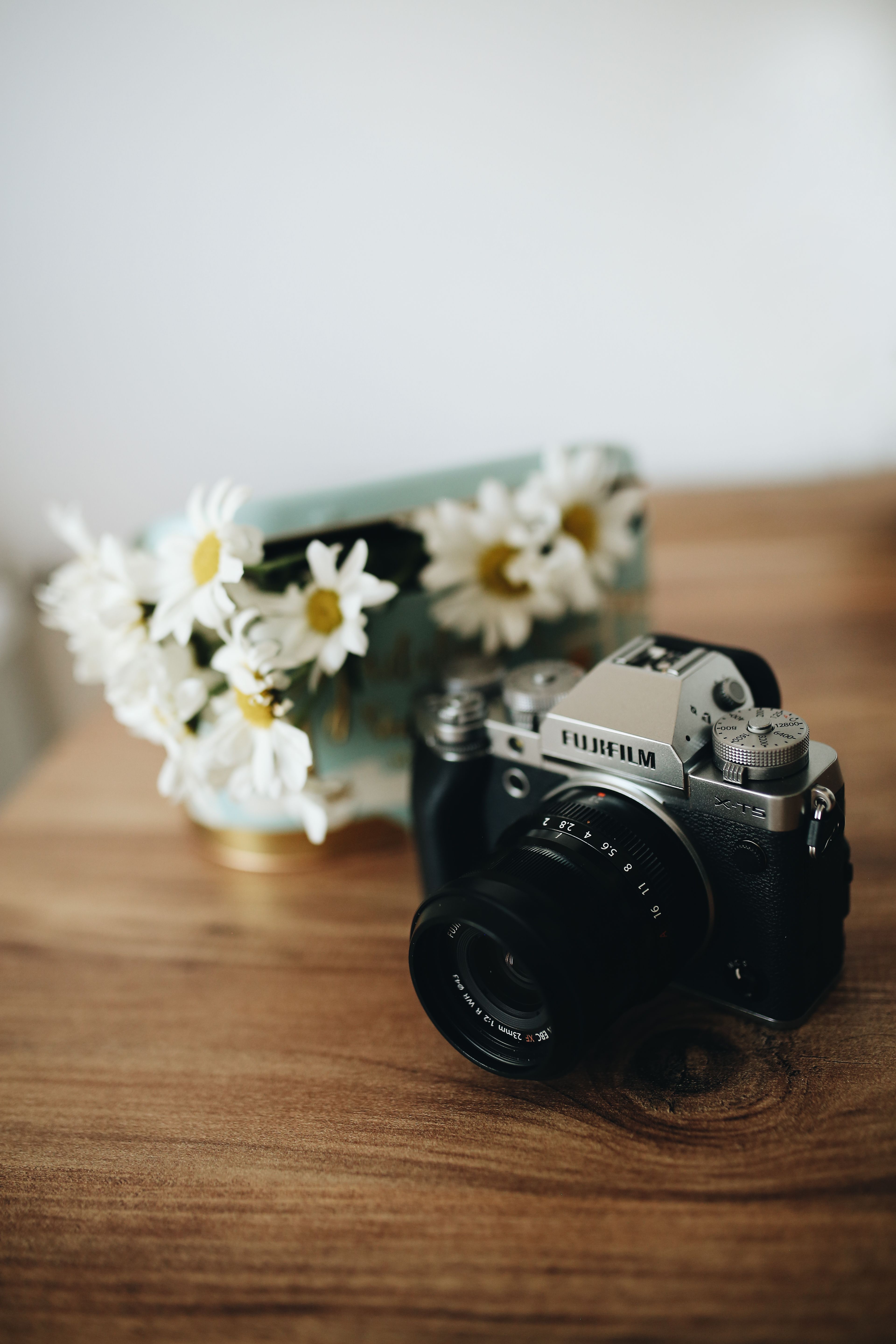 Close-up of a Camera Standing on a Table next to Flowers · Free Stock Photo