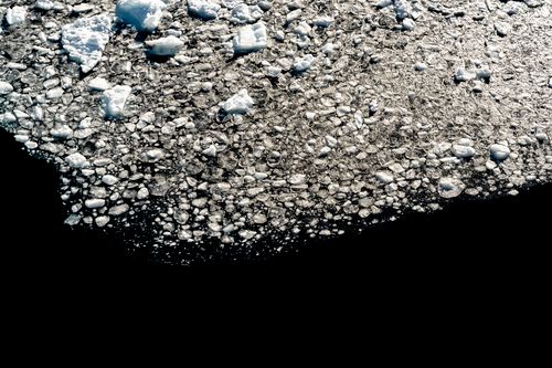Free A stunning aerial view of ice floes across the dark Antarctic waters, reflecting sunlight. Stock Photo