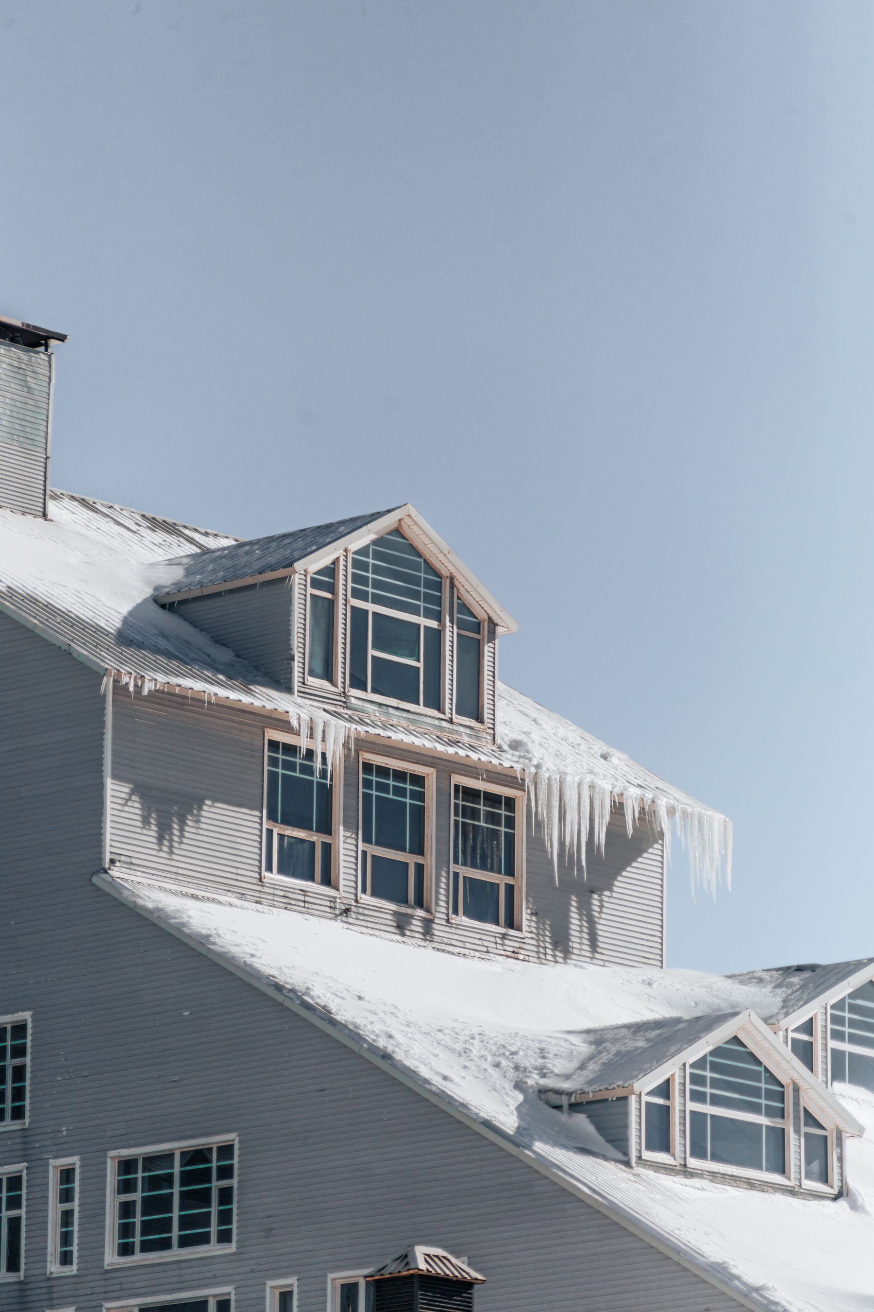 Snow-covered house with icicles hanging from the roof edge