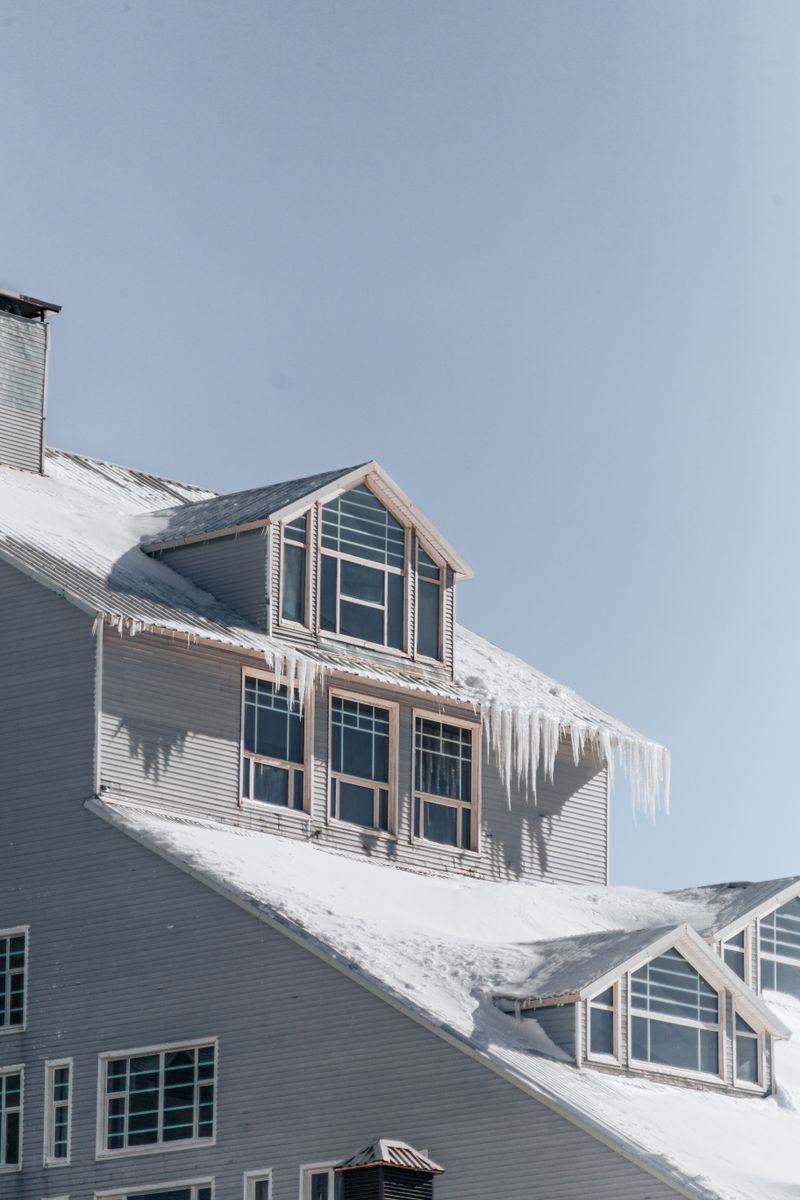 Snow-covered house with icicles hanging from the roof edge
