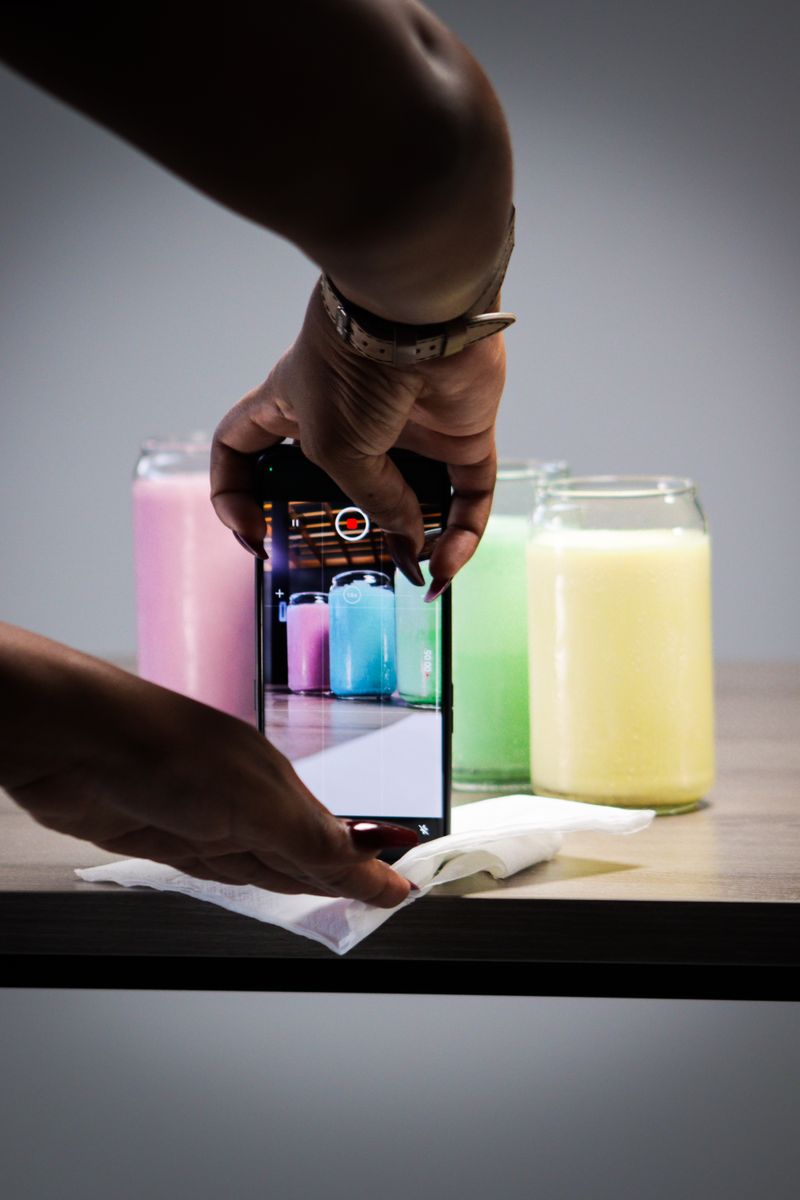 Hands filming colorful product jars with a smartphone