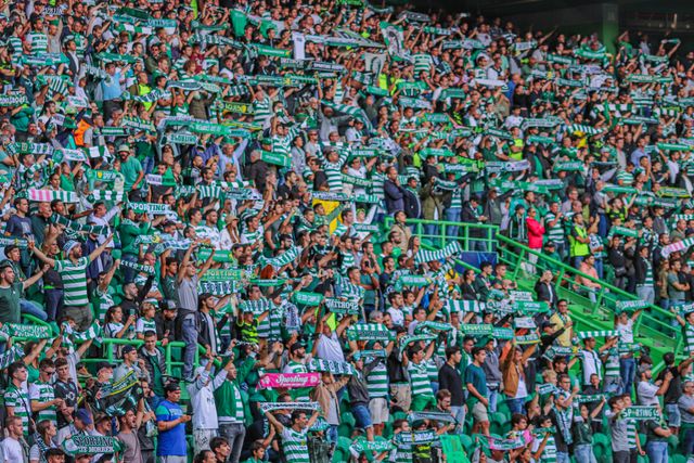 A crowd of football supporters cheering with scarves raised — photo by Beachbumology on Pexels