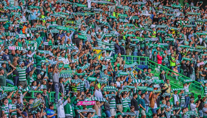 Football fans with scarves cheering at a stadium in Lisbon