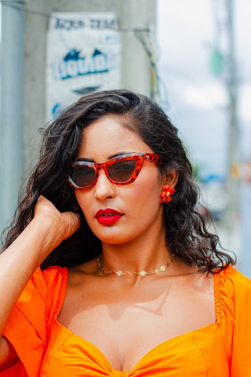 A woman in an orange dress and sunglasses