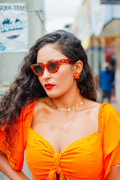 A woman in an orange top and sunglasses