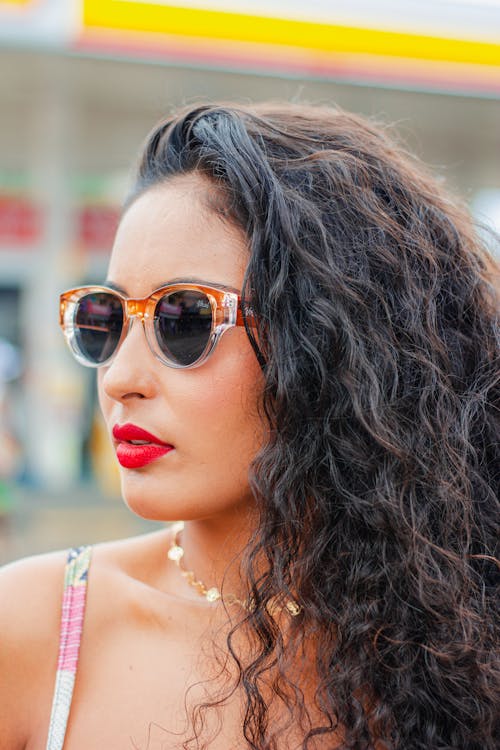 Photo of a Young Brunette Wearing a Red Lipstick and Sunglasses